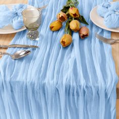 the table is set with tulips and silverware, along with blue napkins