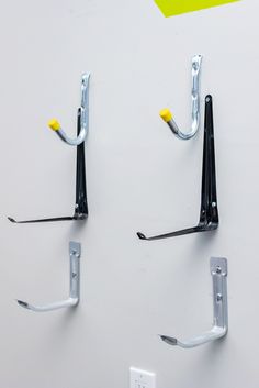 two hooks are attached to the wall with screws and nails on them, one is yellow