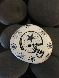 a painted rock with a helmet and stars on it sitting in front of some rocks