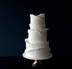 a three tiered white wedding cake with ruffles