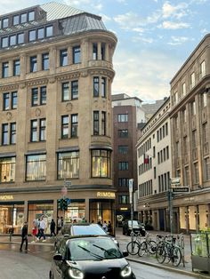 a car is driving down the street in front of some buildings and people walking by