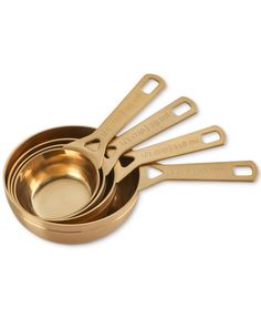 four gold measuring cups with spoons in them