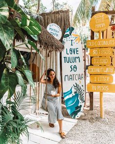 a woman standing next to a sign that says i love tuluum so mataha