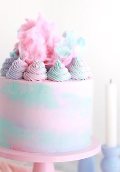 a pink and blue cake with frosting sprinkles on top is shown