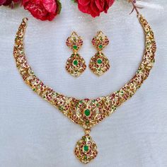 A light weight elegant necklace set in gold plated 22k silver set with precious freshwater pearls and synthetic rubies and emeralds. The earrings come with a bombay screw closure. Weight 31 GMs Festive 22k Gold Emerald Necklace, Gold Emerald Necklace With Intricate Design For Festive Occasions, Gold Emerald Necklace With Intricate Design For Celebration, 22k Gold Emerald Necklace For Festive Occasions, Festive Gold Emerald Necklace With Intricate Design, Gold Round Emerald Necklace In Temple Jewelry Style, Gold Temple Jewelry Style Emerald Necklace, 22k Gold Green Temple Necklace For Celebration, Green 22k Gold Temple Necklace For Celebration