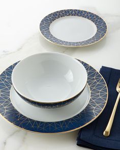 two blue and white plates with gold trims on them, one has a fork in it