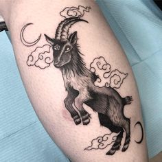 a goat tattoo on the leg of a person with clouds in the sky behind it