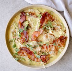 a pizza with bacon, cheese and other toppings in a bowl on a table