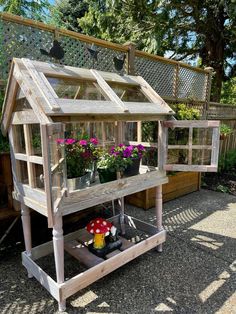 a small wooden greenhouse with potted plants in it