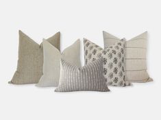 four pillows with different patterns on them, all lined up in a row and facing the same direction