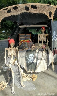 two skeletons are sitting in the trunk of a car decorated for halloween with skeleton decorations