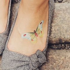 a woman's foot with a butterfly tattoo on it