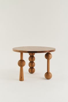 a wooden table with three legs and two balls on the top, against a white background