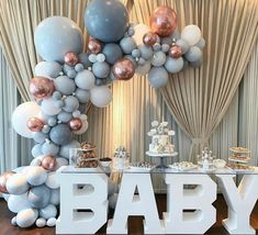 a baby shower is set up with balloons, cake and desserts on the table