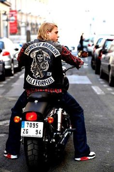 a man riding on the back of a motorcycle down a street