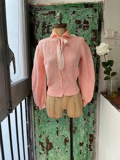 a mannequin wearing a pink sweater with a bow on it's neck