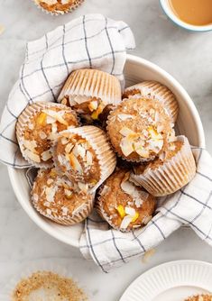 a bowl filled with muffins sitting on top of a table next to a cup of coffee