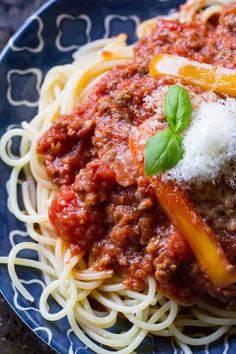 a plate of spaghetti with sauce and cheese on top, sitting on a blue patterned plate