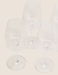 five clear wine glasses with one empty glass on the bottom and four filled ones in front