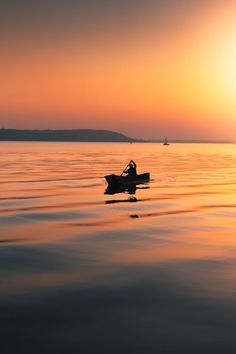 a person in a small boat on the water at sunset