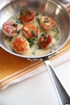 some scallops are in a silver pan on a yellow and white table cloth