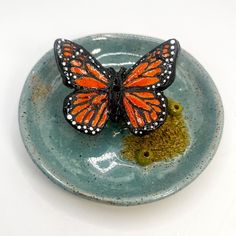 an orange and black butterfly sitting on top of a blue plate