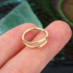 a close up of a person's hand holding a gold ring