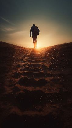 a person walking up a hill towards the sun