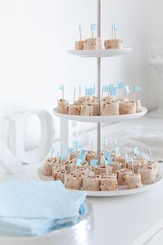 three tiered cake plate with cupcakes and flags on them, sitting on a white table