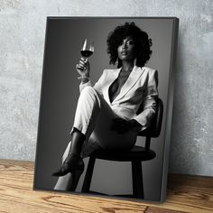 a black and white photo of a woman holding a glass of wine on a chair