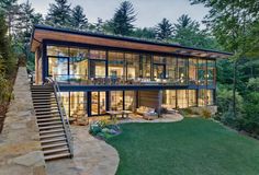 a large modern house in the woods with stairs leading up to it's upper level