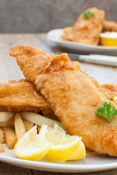 fish and fries on a plate with lemon wedges