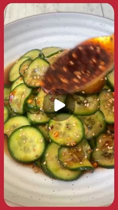 a white plate topped with sliced cucumbers and sauce