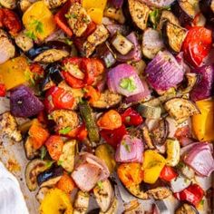 a sheet pan filled with roasted vegetables on top of a white table cloth next to a fork