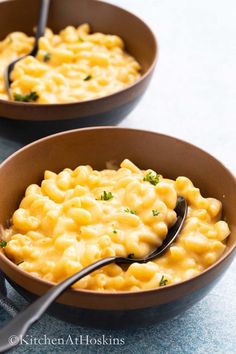 two brown bowls filled with macaroni and cheese on top of a blue counter