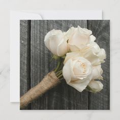 a bouquet of white roses sitting on top of a wooden table