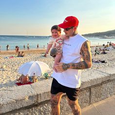 a man holding a baby on the beach