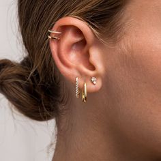 a woman wearing three different types of ear piercings on her left ear, and one with