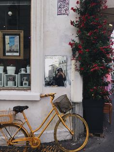 a yellow bike parked in front of a building with flowers on the window sill