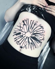 a woman's back with scissors and other tools on her stomach, all in the shape of a circle