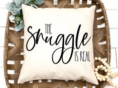 a pillow that says the snuggle is real on top of a wicker basket