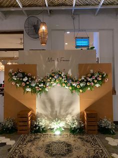 a decorated stage set up with flowers and greenery on the front, in an indoor setting