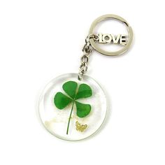 a glass keychain with a four leaf clover and the word love on it