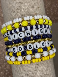 The ultimate bracelet listing for any University of Michigan fan! Go Wolverines! These bracelets are SOLD INDIVIDUALLY & as a STACK of 10! If wanting multiple bracelets, please add each one individually to your cart! Bracelets with letter beads can be personalized to exchange for a different word/name or player number. PERSONALIZATION IS *ONLY* FOR BRACELETS THAT COME WITH LETTER BEADS! (This is important as we have different price points for our goods!) Please use the personalization box if wanting this; otherwise, your bracelet will come as pictured! Personalization Box: PERSONALIZATION ONLY APPLIES TO BRACELETS PICTURED WITH LETTERED BEADS! Please add name/word/player number exactly as you want it on your bracelet. We use Czech glass beads and 18k gold plated beads to create these spiri Go Blue Michigan, Ncaa Basketball Team, Ncaa Football Teams, Blue Bracelets, Items For College, Football Bracelet, Inspired Bracelets, University Of Michigan Wolverines, Multiple Bracelets