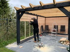 a man is working on the roof of a wooden structure with tools and equipment around it