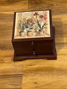 a wooden box sitting on top of a hard wood floor covered in flowers and plants