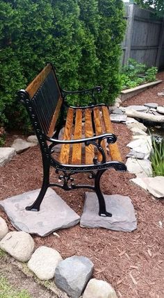 a wooden bench sitting on top of a stone slab in front of a garden pond