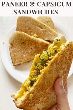 a hand holding up a sandwich with scrambled eggs and spinach in it on a white plate