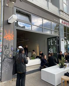 a group of people sitting at tables in front of a building with graffiti on it