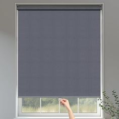 a woman is pointing at the blinds in her living room